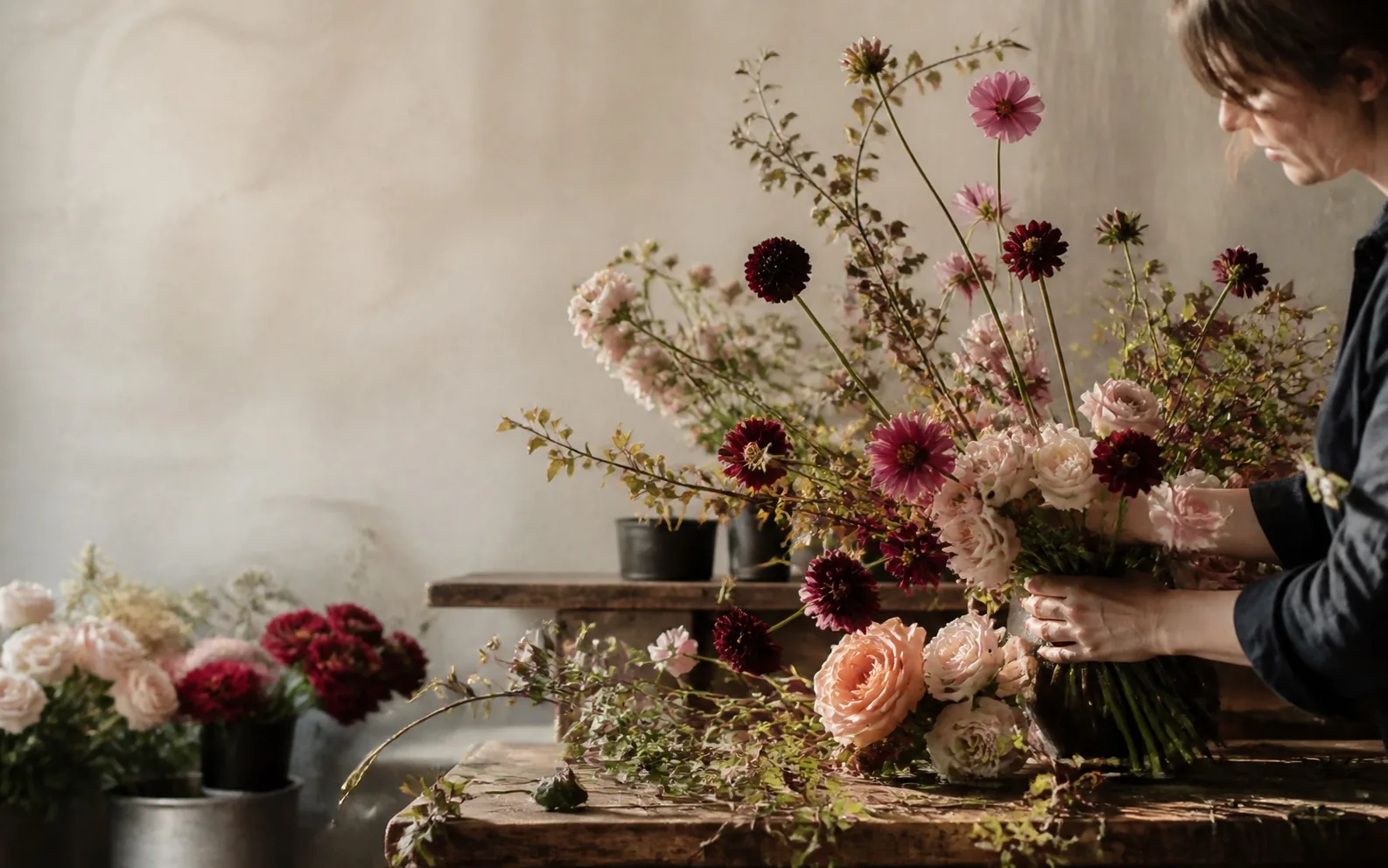 Fleuriste composant un grand bouquet de saison dans l’atelier
