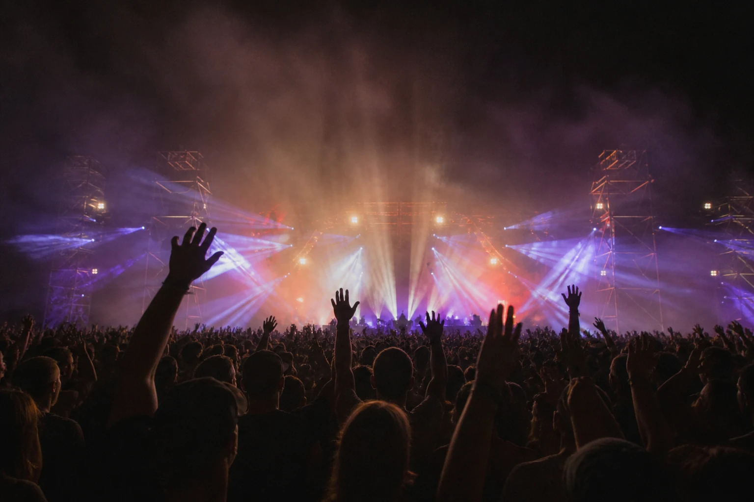 Foule illuminée devant la grande scène d'un festival de nuit