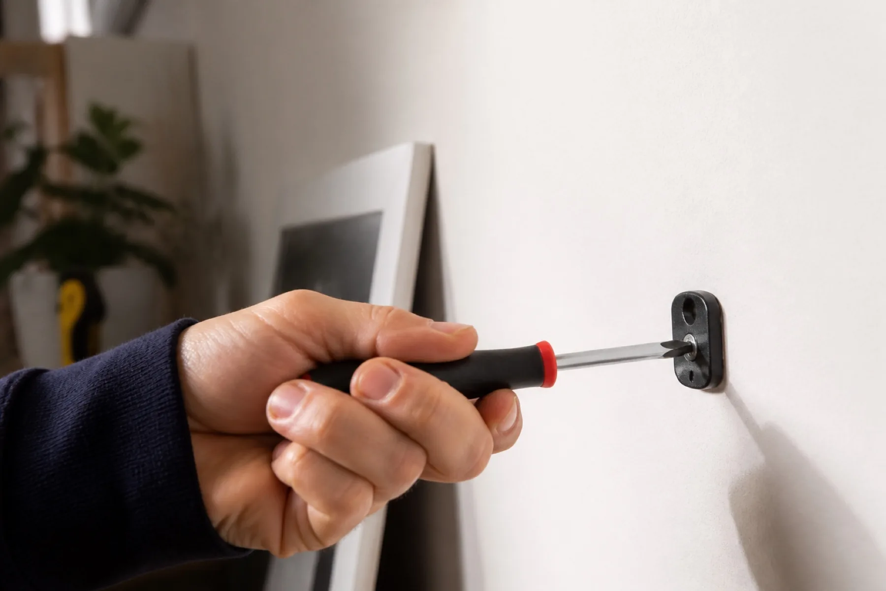 Main posant précisément une fixation sur un mur intérieur propre