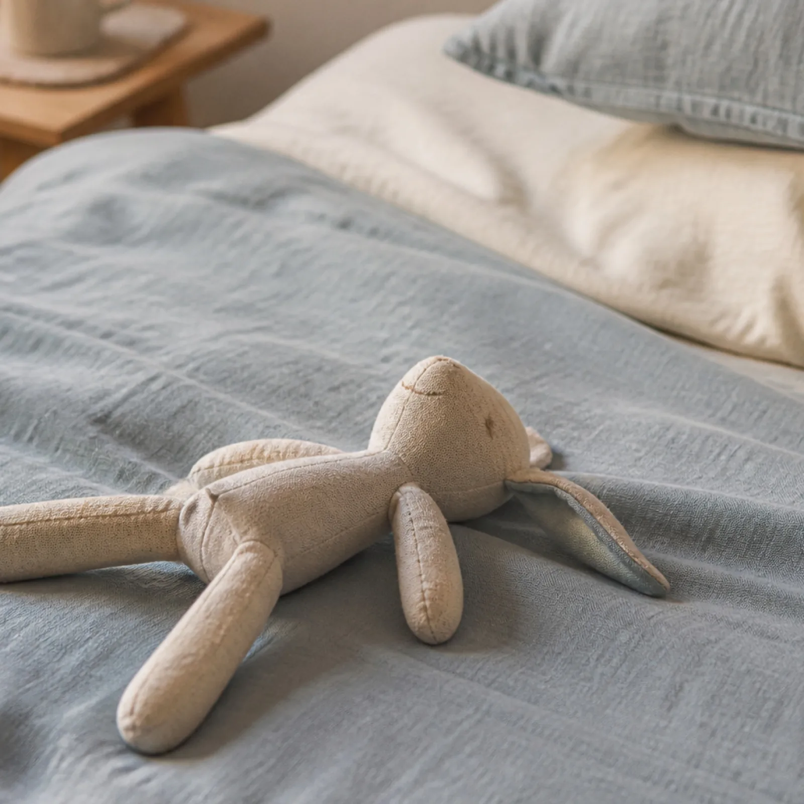Peluche en tissu posée sur un lit fait