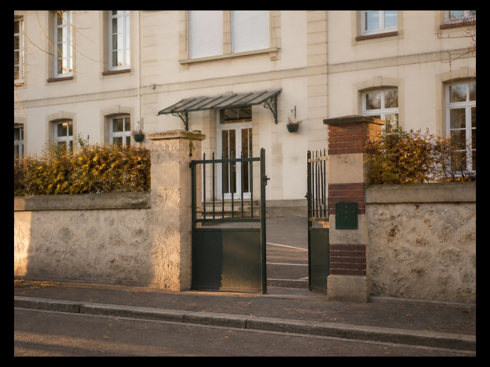 Grille d’école vue depuis le trottoir, fin de journée