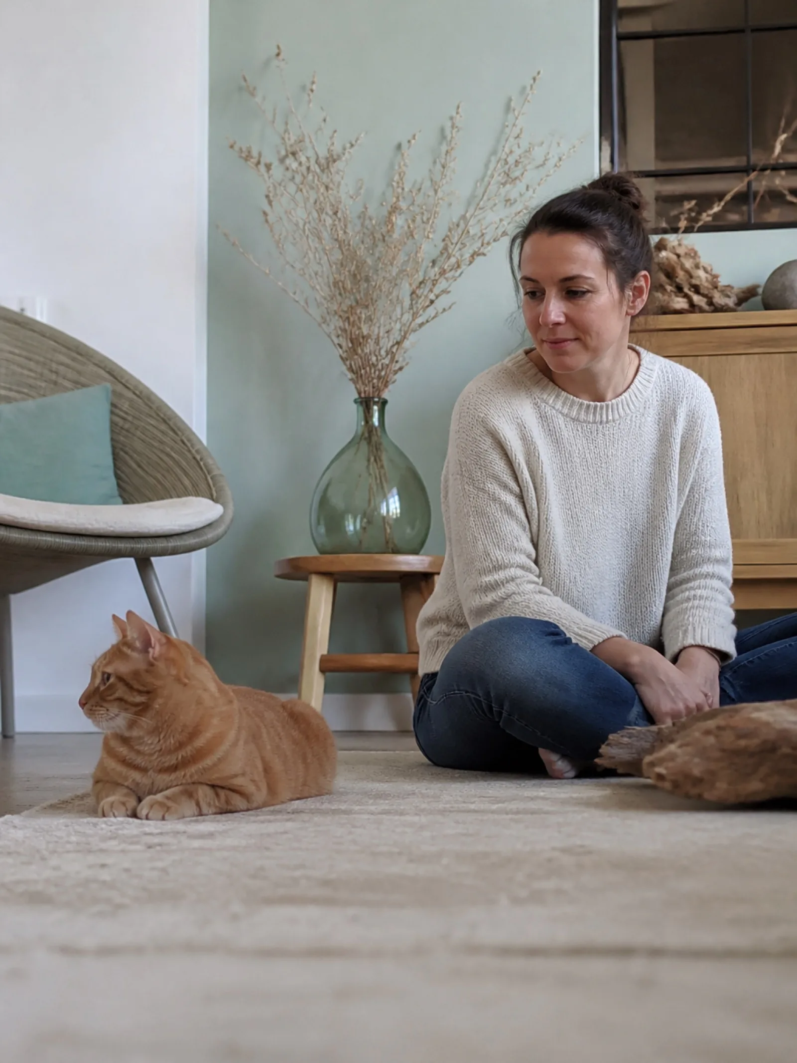 Gardienne assise au sol près d’un chat dans son salon